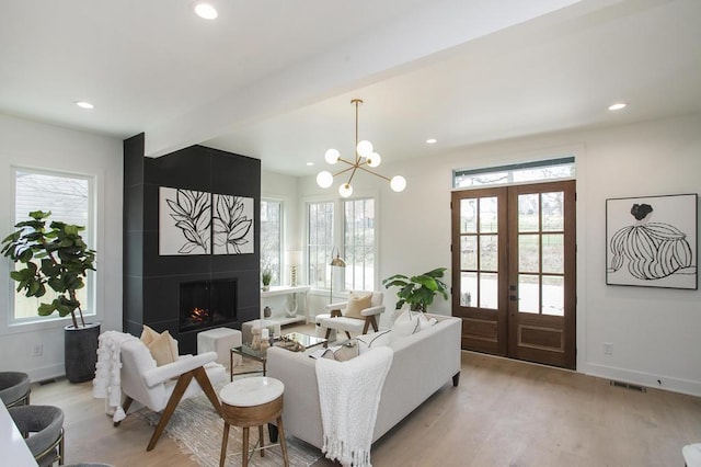 living area featuring light wood-style floors, a wealth of natural light, a large fireplace, and baseboards