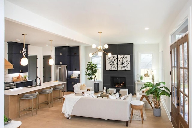 living area with recessed lighting, a fireplace, light wood finished floors, and an inviting chandelier