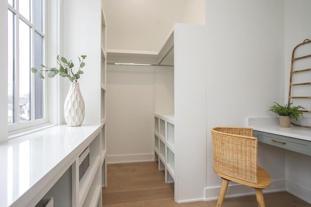 spacious closet featuring light wood-style flooring and built in desk