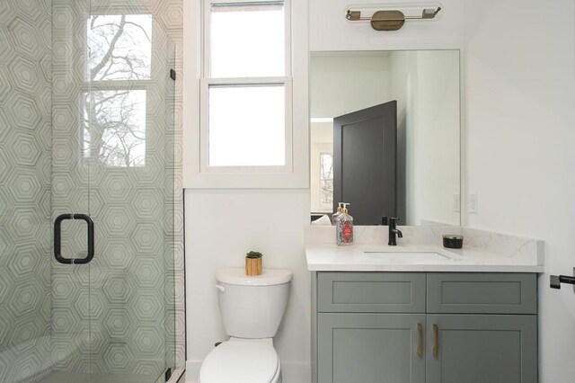 bathroom with toilet, tiled shower, and vanity