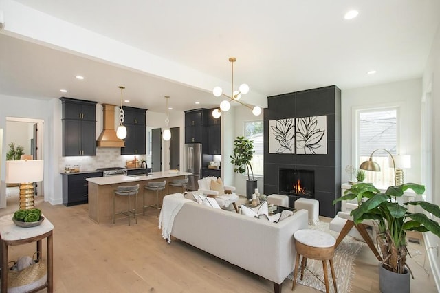 living area with recessed lighting, a large fireplace, and light wood finished floors