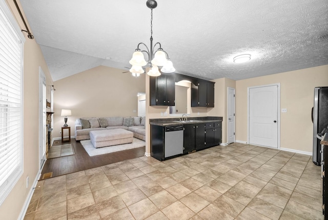 kitchen featuring vaulted ceiling, sink, a chandelier, stainless steel appliances, and a textured ceiling