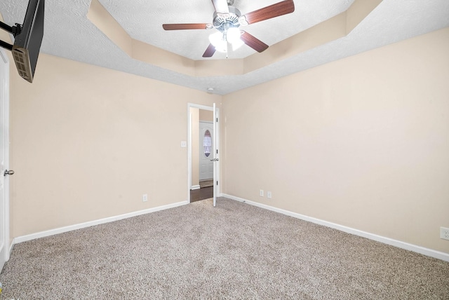 spare room featuring a raised ceiling, ceiling fan, carpet floors, and a textured ceiling