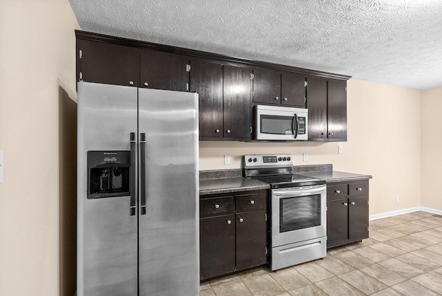 kitchen with dark brown cabinets, stainless steel appliances, a textured ceiling, and light tile patterned flooring