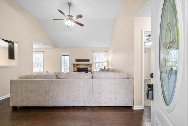 living room with ceiling fan, plenty of natural light, dark hardwood / wood-style flooring, and vaulted ceiling