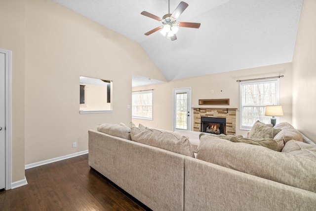 living room with plenty of natural light, lofted ceiling, dark hardwood / wood-style flooring, and a stone fireplace