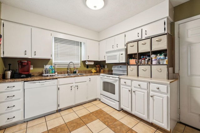 kitchen featuring light tile patterned flooring, sink, white cabinets, and white appliances