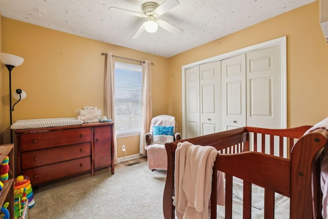 bedroom with ceiling fan, light colored carpet, a closet, and a textured ceiling