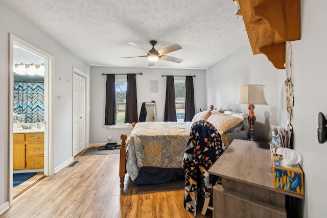 bedroom featuring ceiling fan, ensuite bathroom, a textured ceiling, and light wood-type flooring