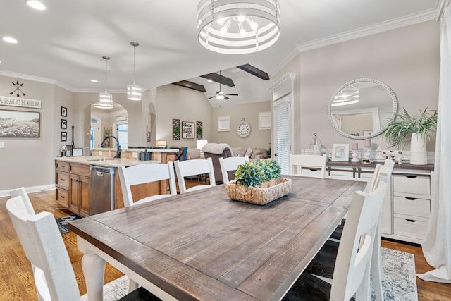 dining space featuring lofted ceiling, sink, light hardwood / wood-style flooring, ornamental molding, and ceiling fan