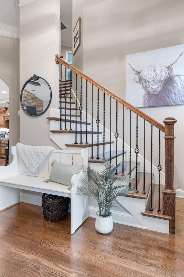 stairway featuring hardwood / wood-style flooring, ornamental molding, and a towering ceiling