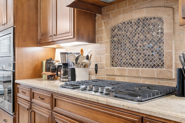 kitchen with tasteful backsplash, appliances with stainless steel finishes, and light stone counters