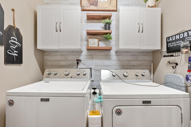 laundry area with separate washer and dryer and cabinets