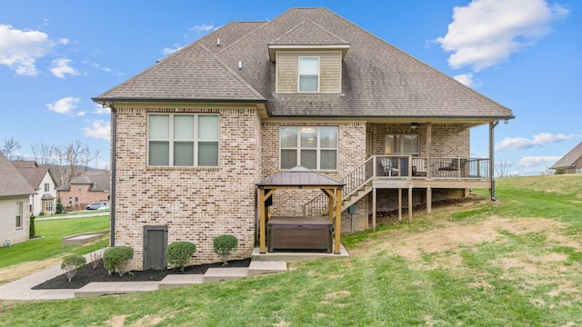 rear view of property featuring a hot tub, a gazebo, and a lawn