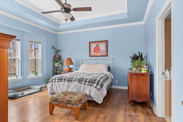 bedroom with a raised ceiling, ornamental molding, hardwood / wood-style floors, and ceiling fan