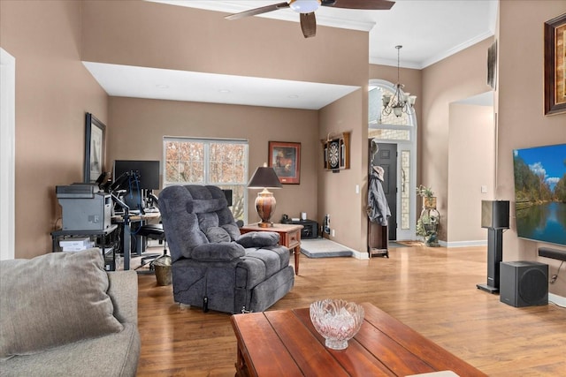 living room featuring hardwood / wood-style floors, ceiling fan with notable chandelier, and ornamental molding