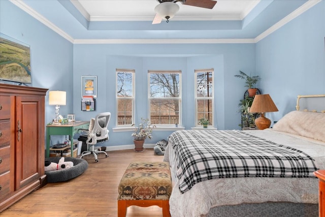 bedroom featuring ceiling fan, ornamental molding, a tray ceiling, and light hardwood / wood-style floors