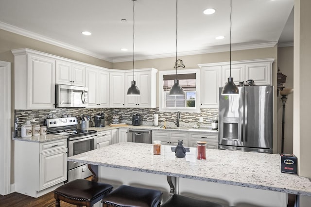 kitchen with hanging light fixtures, a kitchen breakfast bar, white cabinets, and appliances with stainless steel finishes