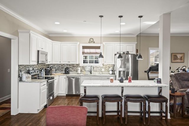 kitchen with hanging light fixtures, white cabinetry, appliances with stainless steel finishes, and light stone countertops