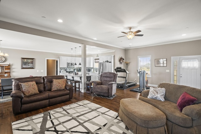 living room with dark hardwood / wood-style flooring, crown molding, and ceiling fan with notable chandelier