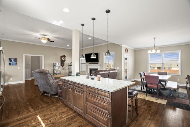 kitchen with light stone counters, dark hardwood / wood-style floors, a kitchen breakfast bar, and pendant lighting