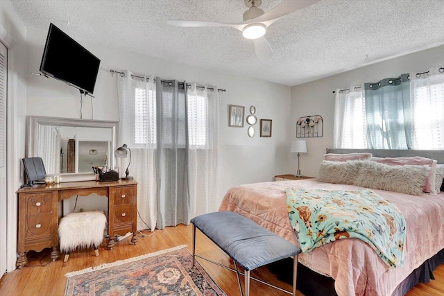 bedroom featuring multiple windows, ceiling fan, a textured ceiling, and light wood-type flooring