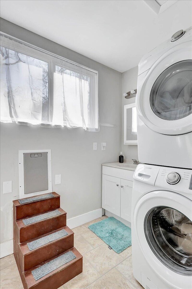 laundry area featuring stacked washer and dryer and cabinets