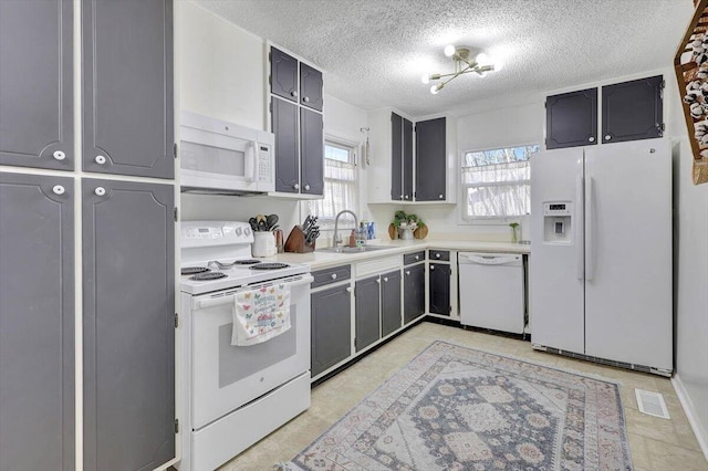 kitchen with sink, white appliances, and a textured ceiling