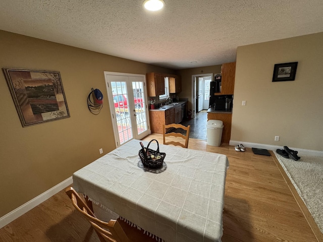 dining room with light hardwood / wood-style floors, french doors, and a textured ceiling