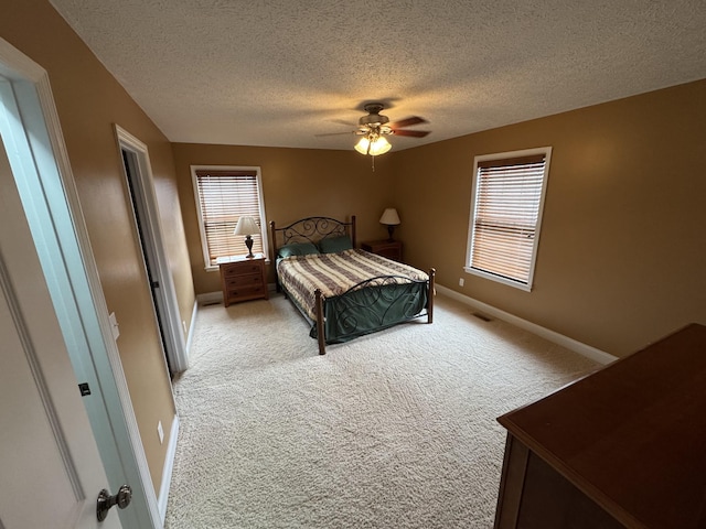 bedroom featuring light carpet, multiple windows, and a textured ceiling