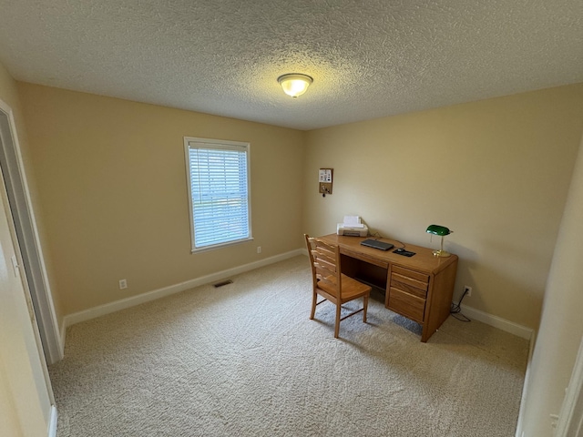 carpeted home office featuring a textured ceiling