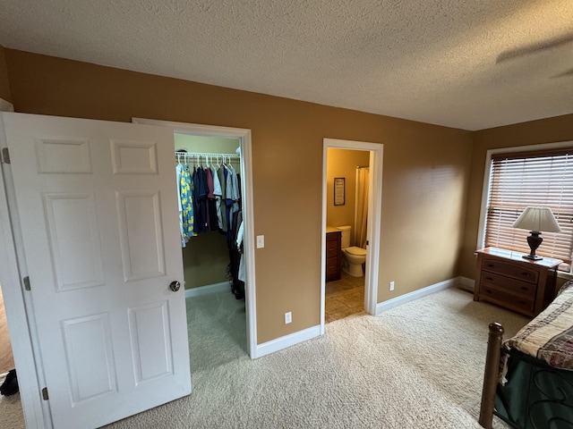 carpeted bedroom with a spacious closet, connected bathroom, a textured ceiling, and a closet