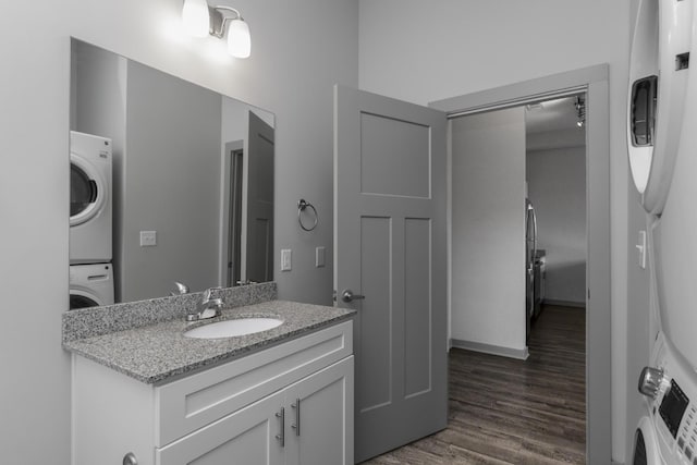 bathroom featuring vanity, stacked washer and clothes dryer, and hardwood / wood-style floors