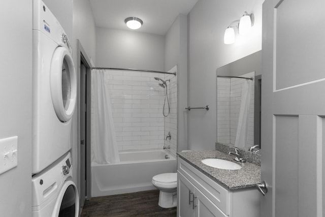 full bathroom featuring hardwood / wood-style floors, stacked washer and dryer, vanity, toilet, and shower / bathtub combination with curtain