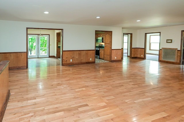 unfurnished room with wooden walls and light hardwood / wood-style floors