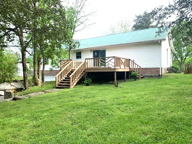 rear view of house with a wooden deck and a yard