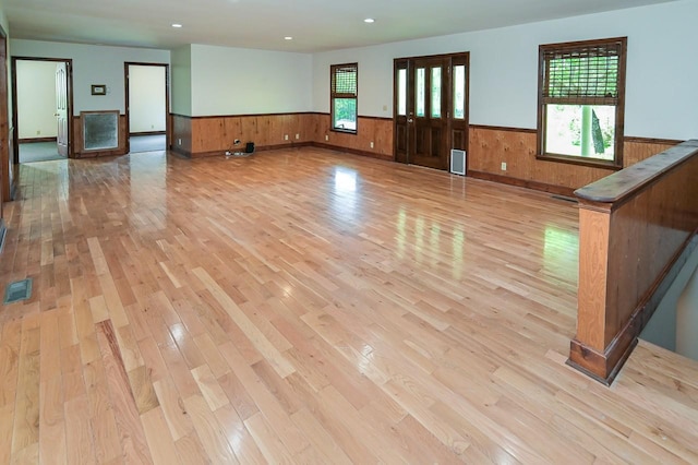 unfurnished room with plenty of natural light, wood walls, and light hardwood / wood-style flooring