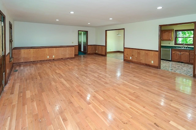 spare room featuring wooden walls, light hardwood / wood-style floors, and sink