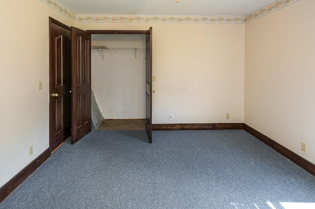 unfurnished bedroom featuring dark carpet and a closet