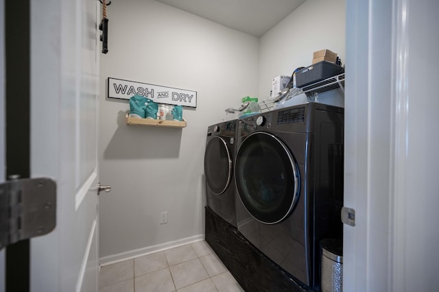 clothes washing area with washing machine and dryer and light tile patterned floors