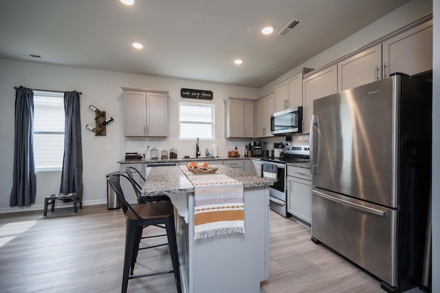 kitchen featuring stainless steel appliances, sink, a center island, and gray cabinetry