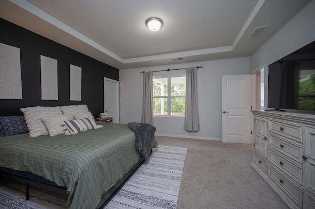 bedroom with light carpet and a raised ceiling