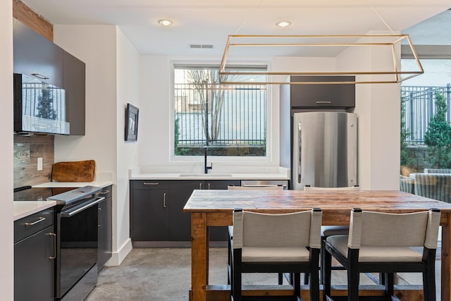 kitchen featuring black range with electric stovetop, sink, stainless steel refrigerator, and backsplash