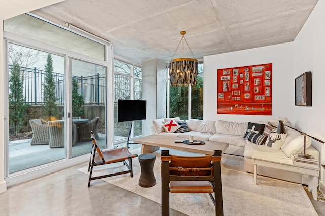 living room with an inviting chandelier, a wall of windows, and concrete flooring