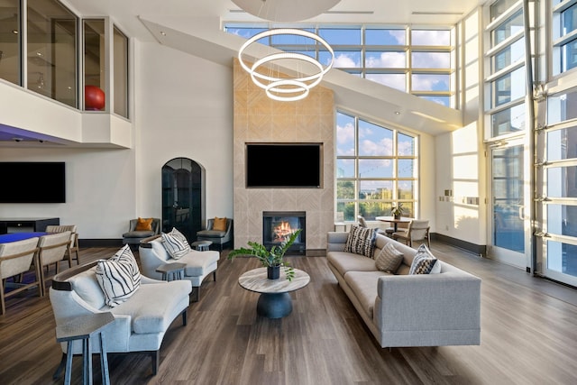 living room featuring hardwood / wood-style flooring, floor to ceiling windows, a high ceiling, and a fireplace