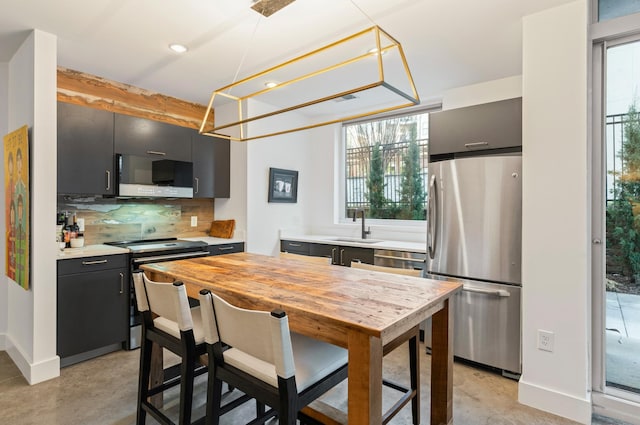 kitchen featuring sink, appliances with stainless steel finishes, pendant lighting, a healthy amount of sunlight, and decorative backsplash