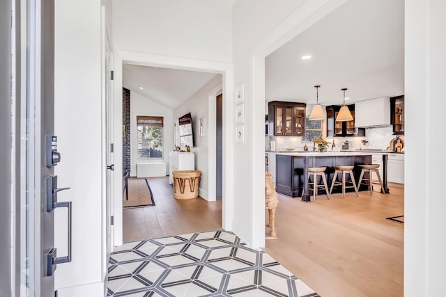 foyer featuring lofted ceiling, radiator, and light wood-type flooring