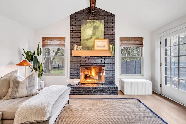 living area featuring a brick fireplace, a wealth of natural light, and lofted ceiling with beams