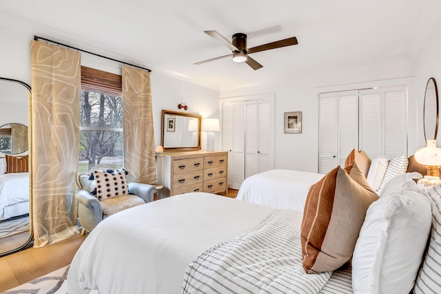 bedroom with multiple closets, hardwood / wood-style flooring, and ceiling fan