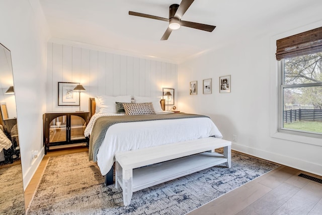 bedroom with ceiling fan, ornamental molding, and light hardwood / wood-style floors